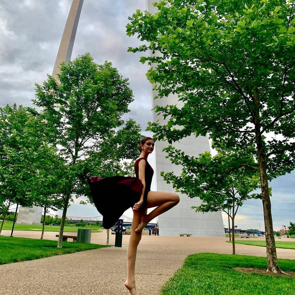 girl dancing in front of the STL Arch