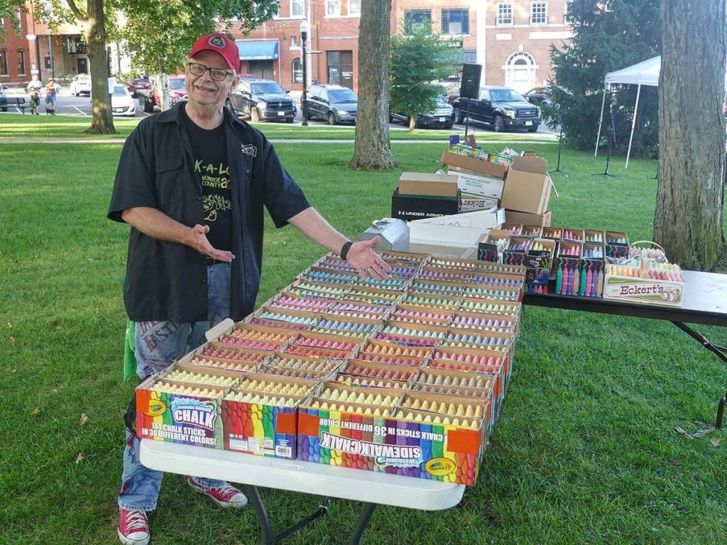 man standing by chalk boxes on a table